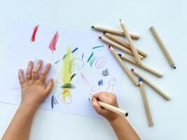 små barn drar med färgad pennor på papper på vit tabell. foto
