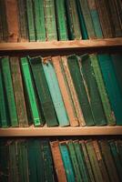 vagt belyst bibliotek med grön böcker anordnad i horisontell linje på hylla foto