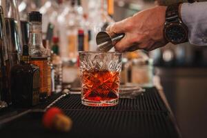 bartender häller en klassisk Martini cocktail in i en glas på en eleganta bar disken. foto