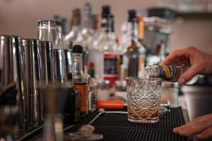 professionell bartender sakkunnigt häller en utsökt cocktail in i en glas på en eleganta bar. foto