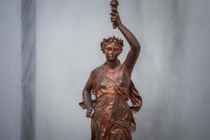 brons staty av kvinna innehav ficklampa på piedestal, isolerat, Nej synlig inskrift eller text foto
