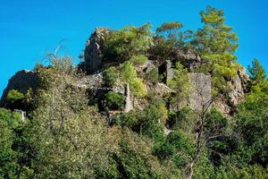ruiner av fästning väggar på trädbevuxen berg sluttningar i de antik stad av olympos, Kalkon foto