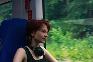 flicka rider en tåg utanför de stad och utseende ut de fönster på en naturlig landskap suddig i rörelse foto