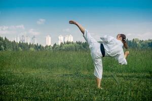 Tonårs flicka Träning karate kata utomhus, utför de uro mawashi geri krok sparka foto