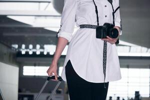 kvinna resande med en resväska och en kamera i de byggnad av de flygplats eller tåg station foto