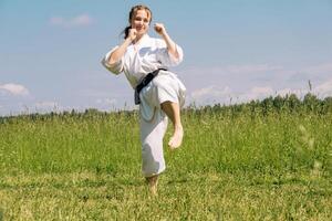 Tonårs flicka Träning karate kata utomhus, förbereder till yoko geri sparka foto