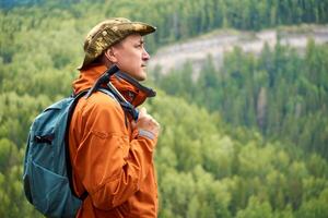 man geolog med en ryggsäck och en geologisk hammare mot de trädbevuxen berg landskap foto