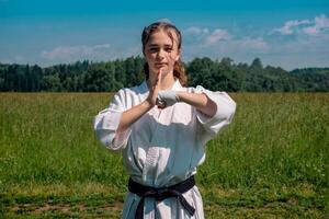 Tonårs flicka Träning karate kata utomhus, hälsningar oss foto