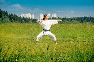 tonåring flicka Träning karate kata utomhus foto