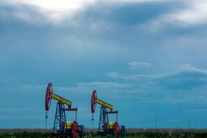 pumpjacks rörelse på ett olja väl i fält under molnig himmel foto