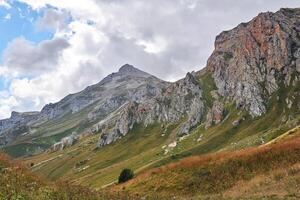 skön berg landskap med en klippig bergsrygg i de distans och ett höst alpina äng i de förgrund foto