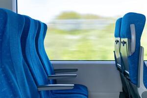 interiör av pendlare passagerare tåg bil, rad av stolar och en rörelsesuddig landskap utanför de fönster foto