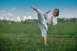 Tonårs flicka Träning karate kata utomhus, utför de uro mawashi geri krok sparka foto