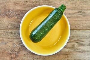 mönstrad grön zucchini squash på en gul tallrik på en trä- bordsskiva foto