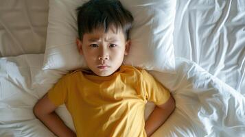 ai genererad topp se av asiatisk pojke liggande i säng med mage värk. sjuk liten barn i sovrum på Hem. diarre och sjukdom i barn foto