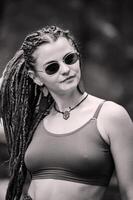 skön flicka med dreadlocks, klädd hippie stil, poser utomhus. foto