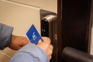 beskurna skott se av turist kvinna använder sig av nyckelkort till låsa upp ett elektronisk dörr i lyx hotell. foto