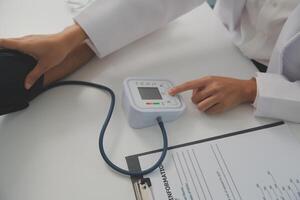 manlig läkare användningar en blod tryck övervaka till kolla upp de kropp tryck och puls av de patienter vem komma till de sjukhus för kontroller, medicinsk behandling och hälsa vård begrepp. foto