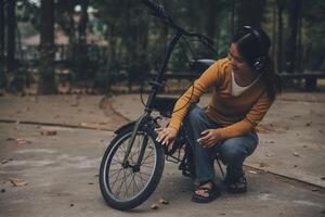 Lycklig ung asiatisk kvinna medan ridning en cykel i en stad parkera. hon log använder sig av de cykel av transport. miljömässigt vänlig begrepp. foto