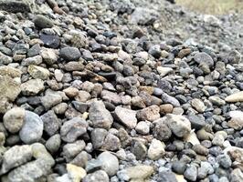 grå grus stenar för de konstruktion industri. mound av granit grus, stenar, krossad sten närbild. grov sömlös textur, konstruktion material bakgrund. foto