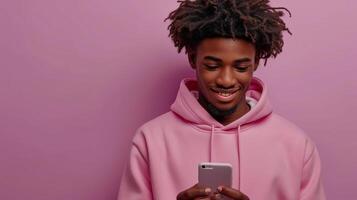 ai genererad isolerat ljus lila bakgrund med tonåring kille i rosa luvtröja innehav mobiltelefon pekande på smartphone använder sig av mobil digital appar. foto