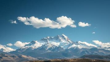 ai genererad majestätisk bergen capped med snö, under en klar blå himmel med mjuk, vit moln. foto
