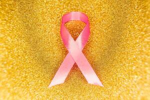 rosa band för bröst cancer medvetenhet, symbolisk rosett Färg höjning medvetenhet på människor levande med kvinnors bröst tumör sjukdom. rosett isolerat med klippning glitter guld bakgrund foto