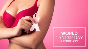 värld cancer dag begrepp bakgrund. ung kvinna granskning henne bröst för klumpar eller tecken av bröst cancer. rosa band. foto