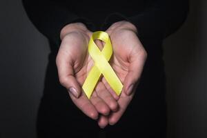 guld band för barn som en symbol av barndom cancer medvetenhet. gul band på hand foto