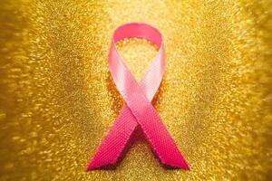 rosa band för bröst cancer medvetenhet, symbolisk rosett Färg höjning medvetenhet på människor levande med kvinnors bröst tumör sjukdom. rosett isolerat med klippning glitter guld bakgrund foto