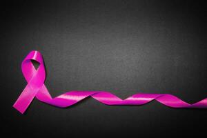 rosa band för bröst cancer medvetenhet, symbolisk rosett Färg höjning medvetenhet på människor levande med kvinnors bröst tumör sjukdom. rosett isolerat med klippning svart bakgrund foto