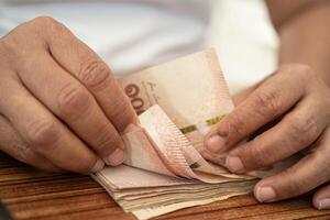 asiatisk företag kvinna innehav thai sedel valuta pengar. foto
