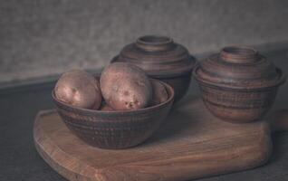 potatisar i en brun tallrik och två lera krukor. filmiska foto