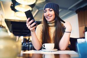 portret av ung kvinna läsning SMS på de telefon i Kafé. tonad. selektiv fokus. foto