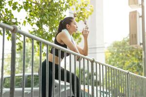 sport asiatisk lady törstig dricka vatten på morgon- joggning friska livsstil foto