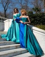 två kvinnor i blå klänningar stå i främre av en trappa. foto