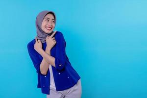 snygg karismatisk ung kvinna med hijab pekande isolerad på ljusblå bakgrund foto