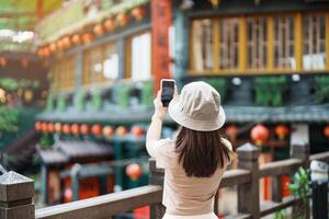 kvinna resande besöker i taiwan, turist tar Foto och sightseeing i jiufen gammal gata by med te hus bakgrund. landmärke och populär attraktioner nära taipei stad. resa begrepp