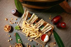 trä- bricka med halv skära smörgås och franska frites foto