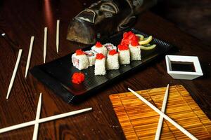 svart tallrik med sushi och ätpinnar foto