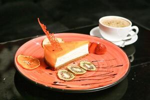 cheesecake skiva på orange tallrik med kaffe kopp foto