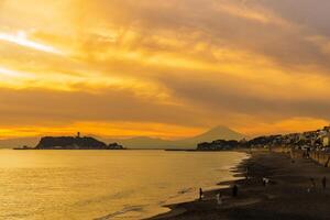 landskap kamakura yuigahama strand med kamakura stad och fujisan berg. skymning silhuett montera fuji Bakom enoshima ö på kamakura, kanagawa, japan. landmärke för turist attraktion nära tokyo foto