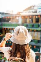 kvinna resande besöker i taiwan, turist med hatt och ryggsäck sightseeing i jiufen gammal gata by med te hus bakgrund. landmärke och populär attraktioner nära taipei stad. resa begrepp foto