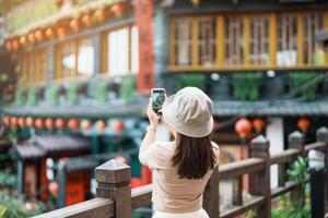 kvinna resande besöker i taiwan, turist tar Foto och sightseeing i jiufen gammal gata by med te hus bakgrund. landmärke och populär attraktioner nära taipei stad. resa begrepp