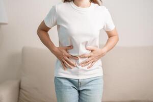 kvinna problem och endometrios, hysterektomi och menstruations- på de soffa på Hem, kvinna har buk värk på grund av till mage smärta, matsmältning med förstoppning eller diarre från mat förgiftning foto