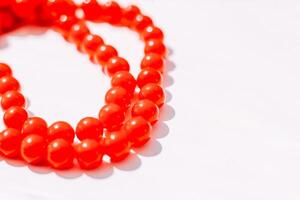 en halsband av röd pärlor på en vit estetisk bakgrund. foto