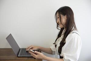 en japansk kvinna kontroll smartphone förbi avlägsen arbete i de små kontor foto