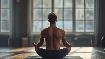 ai genererad se från de tillbaka av en ung man med ett atletisk figur, man praktiserande yoga meditation i en lugn inomhus- miljö. foto