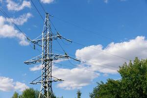 elektrisk nätverk av poler på blå himmel och omgiven förbi grön buskar och träd. hög kvalitet Foto