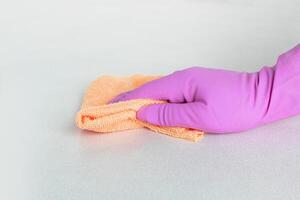 en hand i en rosa handske våtservetter de yta med gul mikrofiber. hög kvalitet Foto